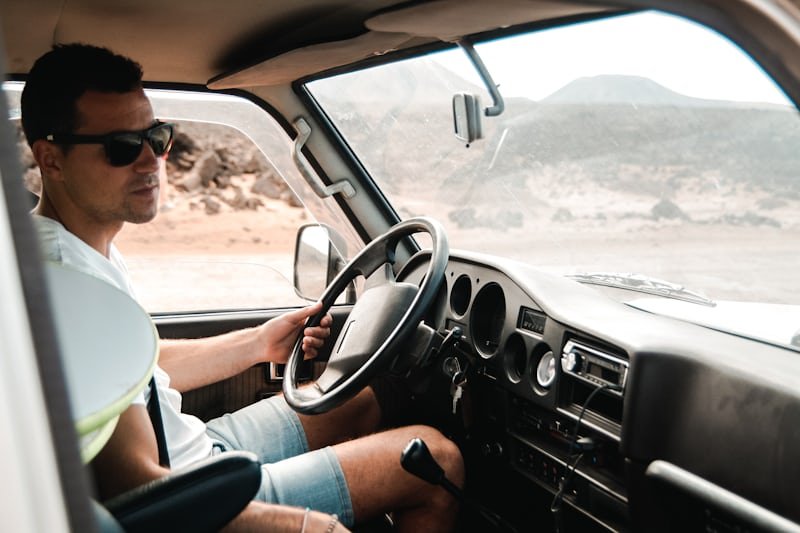 A driver at the wheel of a car, seen from the passenger seat.