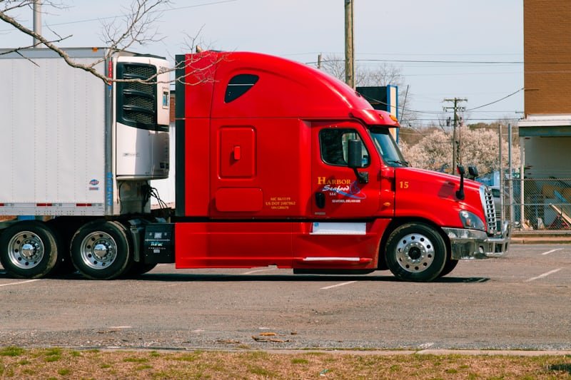 A red prime mover coupled to a trailer, parked side-on.