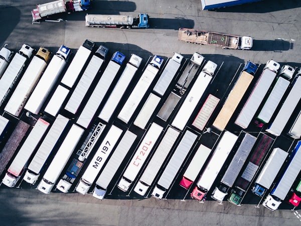 Aerial view of trucks and trailers parked in rows in a freight yard.