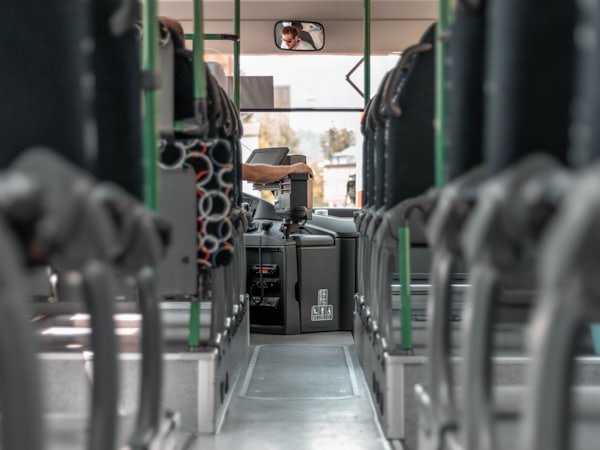 The interior aisle of a bus looking towards the driver's seat.