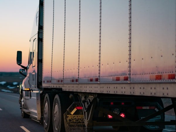 The rear of a semi-trailer on a road at dusk.