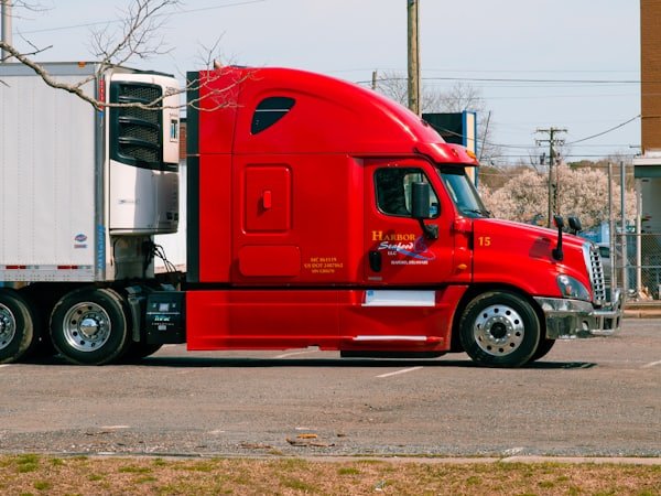 A red prime mover coupled to a trailer, parked side-on.